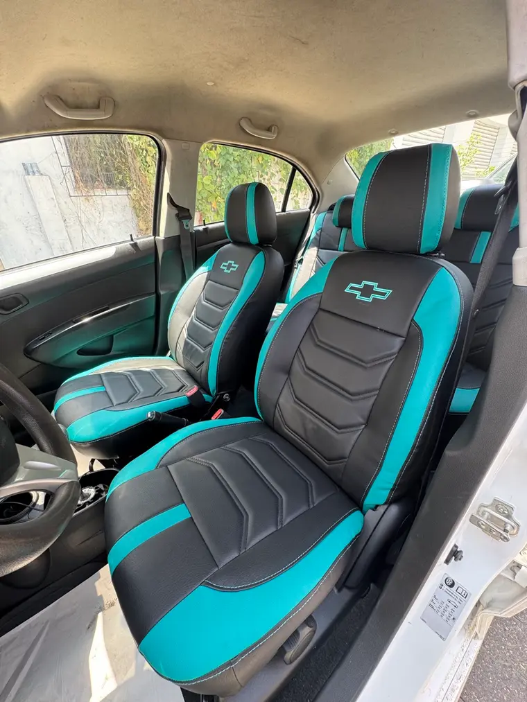 Forros negro con turquesa, chevrones y logo Chevrolet bordado, en un Chevrolet Spark